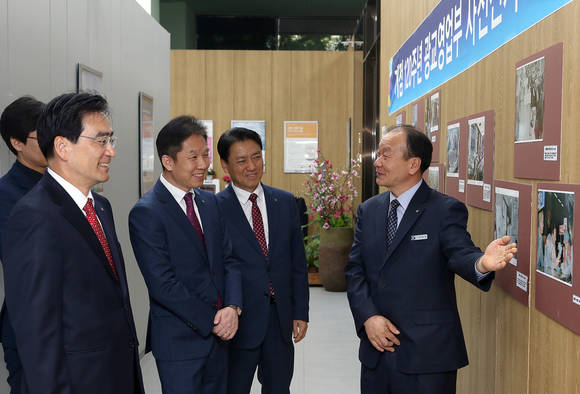 ▲ 신한은행 광교영업부에서 진행된 ‘신한은행 광교영업부 개점 120주년 기념 나눔행사’에서 정원만 초록우산어린이재단 부회장 주철수(왼쪽 첫 번째), 신한은행 부행장(왼쪽 두 번째)이 광교 갤러리에 전시된 사진을 보고 있다.ⓒ신한은행