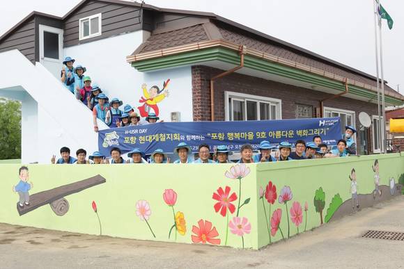 ▲ 지난 23일 봉사활동에 참가한 봉사자들이 자신들이 그린 벽화 앞에서 기념촬영에 임하고 있다.ⓒ현대제철