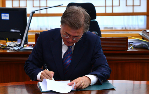 ▲ 문재인 대통령이 청와대 여민관 집무실의 자신의 책상 앞 라운드 테이블에서 참모들의 조언을 들으며 서류에 서명하고 있다. ⓒ뉴시스 사진DB