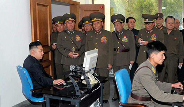 ▲ 군 관련시설을 찾아 PC를 해보는 김정은. 주변에 서 있는 北노동당 고위간부는 김정은이 뭘 하는지도 모를 가능성이 있다. ⓒ北선전매체 화면캡쳐.
