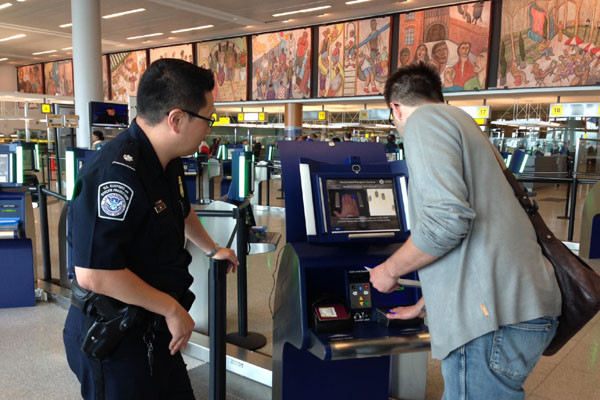 美뉴욕 JFK국제공항에서 키오스크를 통해 입출국 심사를 하는 사람을 돕는 美국토안보부 CBP 요원의 모습. ⓒ美DHS CBP 홈페이지 캡쳐.