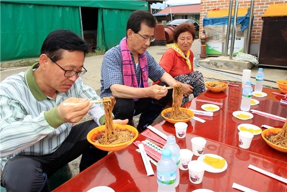 ▲ 이시종 도지사가 22일 경북 경산시에서 중국음식점을 운영하는 사람들로 구성된 짜사모가 만들어준 짜장면을 괴산 청천면 피해복구 주민들과 함께 먹고 있다.ⓒ충북도