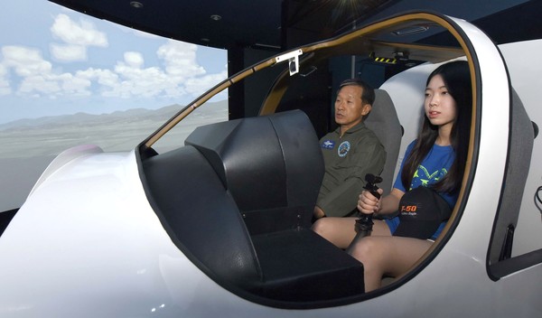 ▲ 캠프에 참가한 한 여학생이 공사 생도들이 받는 모의비행훈련실에서 비행시뮬레이터를 체험하고 있다.ⓒ공군사관학교