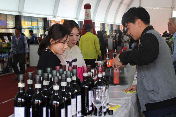 ▲ 지난해 대한민국 와인축제장에서 관광객에게 시음할 와인을 따라주고 있다.ⓒ영동군