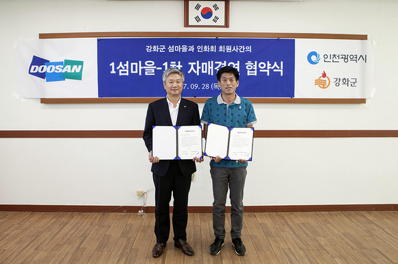 ▲ 두산인프라코어 박성권 전무(사진 왼쪽)와 석포리 손경배 이장이 강화군 삼산면 면사무소에서 ‘1섬마을 1사’ 자매결연협약을 체결했다.ⓒ두산인프라코어