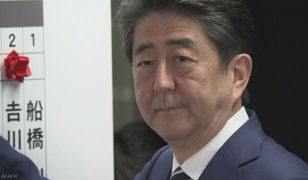 아베 신조 日총리가 승리한 후보들의 이름 위에 꽃을 꽂고 있다. ⓒ日NHK 관련보도 화면캡쳐.