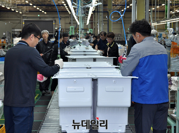 ▲ 진공 성형을 마친 내상에 냉장관련 부품을 조립 중인 직원들 ⓒ 대유위니아 제공