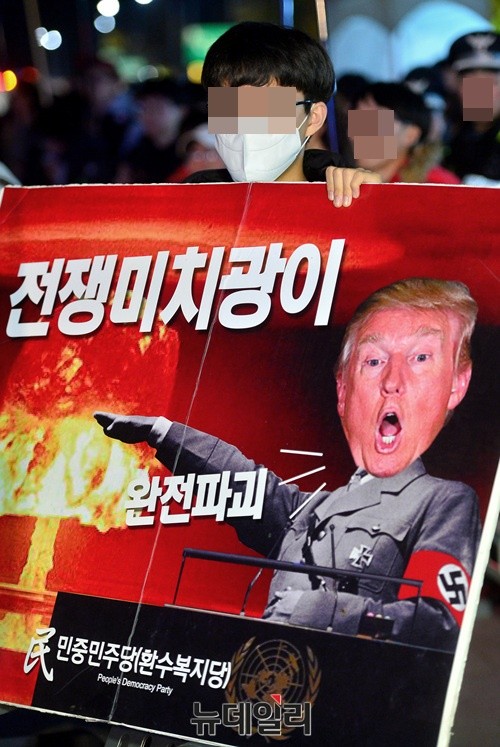 ▲ 한 집회 참석자가 오후 7시 광화문광장에서 'NO 트럼프 공동행동' 주최로 열린 집회에서 트럼프를 전쟁미치광이로 표사한 팻말을 들고 있다.  ⓒ뉴데일리 공준표 기자