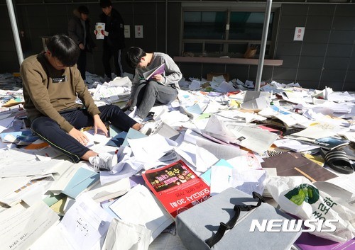 ▲ 포항지진 여파로 2018학년도 대학수학능력시험이 연기된 16일 오전 서울 중구 종로학원 옥상에서 수험생들이 버렸던 참고서와 학습지를 다시 찾고 있다. ⓒ 뉴시스