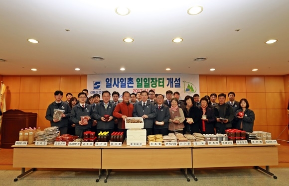 ▲ 농산물 직거래 장터에서 신동아건설 임직원과 덕전마을 주민들이 기념촬영을 하고 있다. ⓒ신동아건설