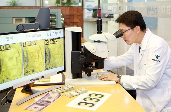 ▲ KEB하나은행 위변조대응센터에서 전자 현미경을 통해 미국 달러화 지폐의 진폐 여부를 감별하고 있는 모습. ⓒKEB하나은행