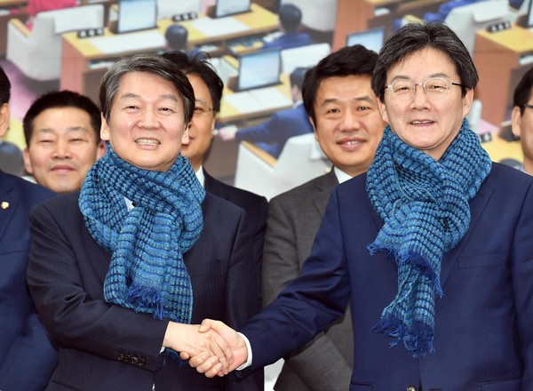 ▲ 안철수 국민의당 대표와 유승민 바른정당 대표가 14일 오후 부산 연제구 부산시의회 대회의실에서 열린 국민통합포럼 세미나에 참석, 각 당원들로부터 선물받은 목도리를 착용한 뒤 악수하고 있다. ⓒ뉴시스