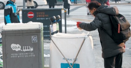 ▲ 서울시 종로구에 설치된 태양광 쓰레기통. 길을 지나던 한 시민이 태양광 쓰레기통이 아닌 일반 쓰레기통에 쓰레기를 버리고 있다. ⓒ조선일보 DB