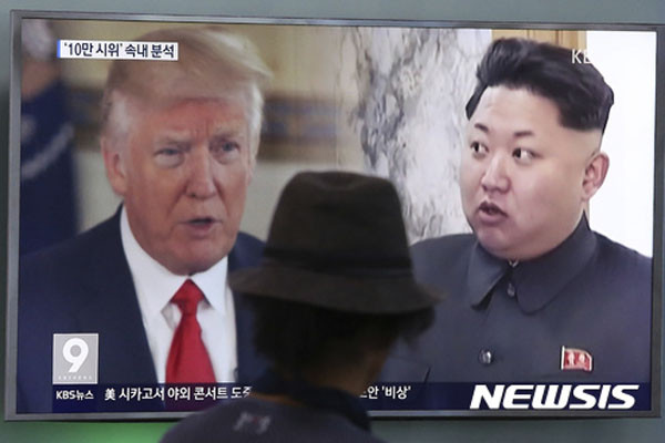 ▲ 한 행인이 트럼프 美대통령과 김정은 간의 대립양상을 보도하는 TV 화면 앞을 지나가고 있다. ⓒ뉴시스. 무단전재 및 재배포 금지.