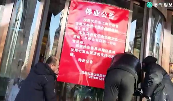 中선양 소재 '칠보산 호텔' 직원들이 폐쇄 공지문을 붙이고 있다. ⓒ동아일보 관련보도 유튜브 영상 캡쳐.