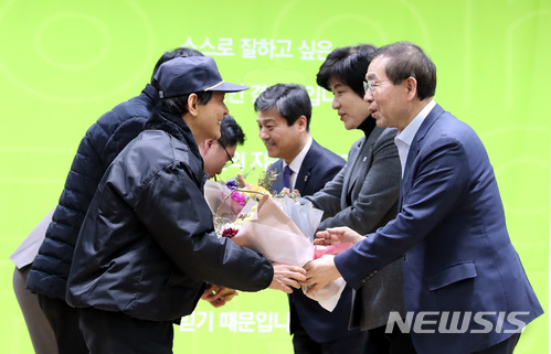 ▲ '아파트 경비노동자 고용안정 설명회'가 열린 5일 오후 서울 성북구청 아트홀에서 박원순 서울시장, 김영주 고용노동부장관이 최저임금 우수 공동주택 입주자 대표, 관리사무소장, 경비원에게 꽃다발을 전달하는 모습.ⓒ뉴시스