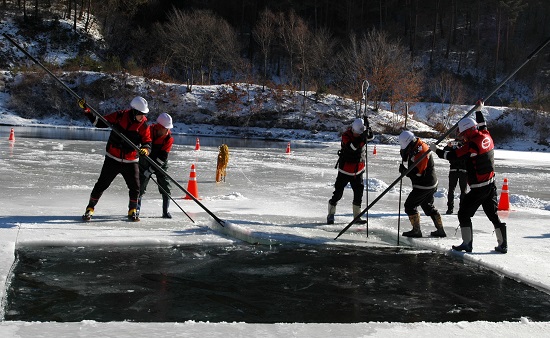 ▲ 산림청 직원들이 결빙된 저수지에서 헬기 담수를 위해 얼음을 깨고 있다.ⓒ산림청