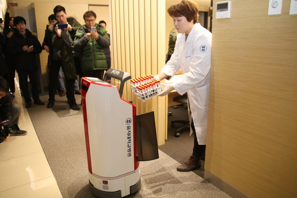 ▲ 대전 을지대학교병원 의료진이 유진로봇의 자율주행 물류배송 로봇 '고카트 미니'에 검체를 싣는 모습. ⓒ연찬모 기자