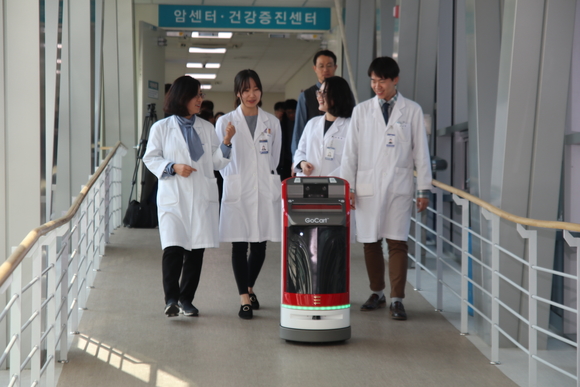 ▲ 대전 을지대학교병원 의료진이 유진로봇의 자율주행 물류배송 로봇 '고카트 미니'와 함께 이동하는 모습. ⓒ연찬모 기자