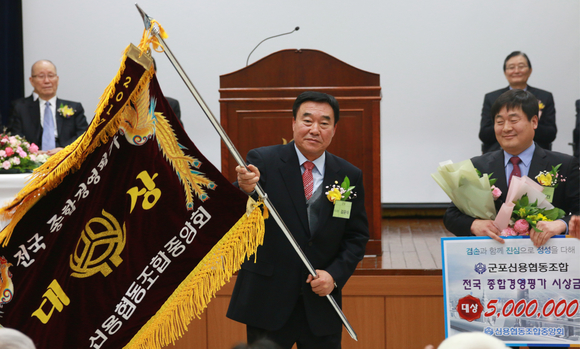 ▲ 신협중앙회는 제45차 정기대의원회에서 전국 898개 신협을 대상으로 실시한 '2017 전국 신협 종합경영평가' 결과를 발표했다. 이날 조합 경영평가에서 대상을 받은 군포신협을 대표해 김윤식 이사장이 대상기를 흔들고 있다.ⓒ신협중앙회