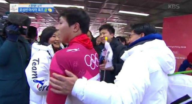 ▲ 더불어민주당 박영선 전 원내대표가 비매품인 국가대표 공급용 평창 롱패딩을 입고, 남자 개인 스켈레톤에서 금메달을 획득한 윤성빈에게 다가서고 있다. ⓒ방송화면 갈무리