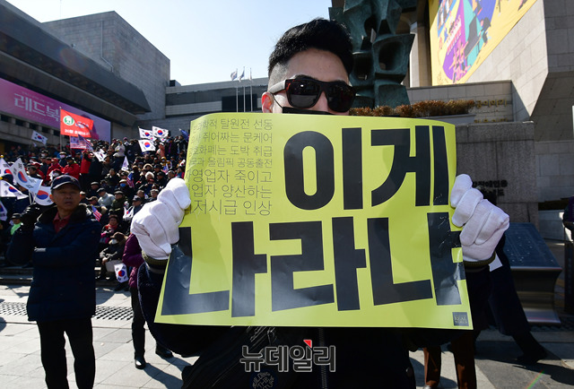 ▲ 99주년 3.1절을 맞아 서울 도심에서 대규모 태극기 집회가 열린 가운데 한 참석자가 '이게 나라냐'라는 구호가 적힌 손피켓을 들어보이고 있다.ⓒ뉴데일리 정상윤 기자