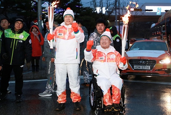 ▲ 김정태 하나금융 회장(왼쪽)은 전선주 대한장애인체육회 훈련육상부장과 지난 8일 오후 강릉시청에서 진행된 평창 동계패럴릭픽 성화봉송 주자로 참여했다. ⓒ하나금융지주