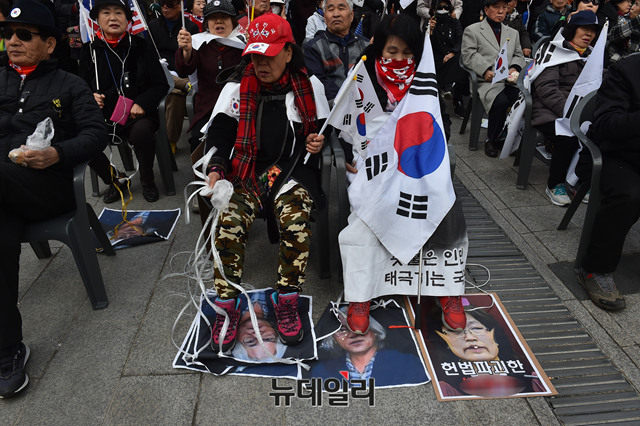 ▲ 10일 오후 2시 서울 중구 대한문 앞에서 '태극기혁명국민운동본부' 주최로 태극기집회가 열린 가운데 일부 참가자들이 문재인 대통령과 이윤택 연극 감독의 얼굴이 합성된 사진을 밟는 퍼포먼스를 벌이고 있다.ⓒ뉴데일리 이종현 기자