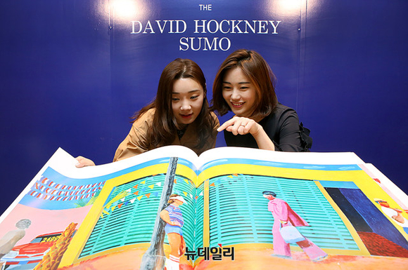 ▲ 현대백화점 무역센터점 9층 오픈 도서관에서 직원들이 영국의 팝아트 화가 '데이비드 호크니'의 작품이 담긴 대형 책을 보고 있다. ⓒ현대백화점