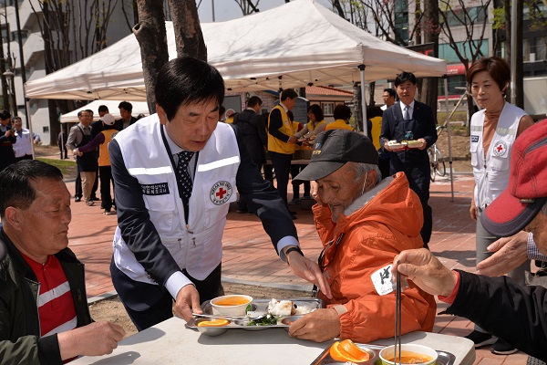 ▲ 김경배 회장이 지난 12일 청주 중앙공원에서 노인들에게 점심 배식을 하고 있다.ⓒ충북적십자사