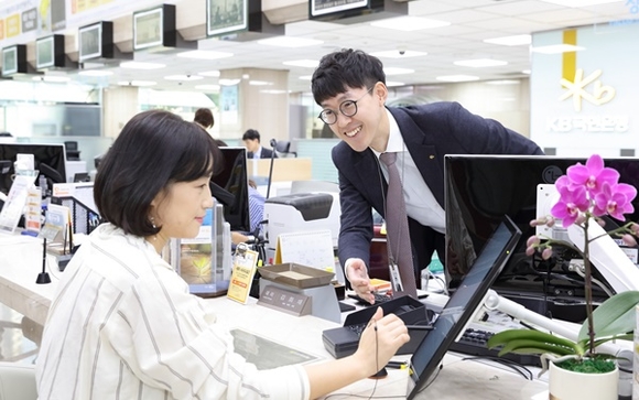 ▲ 국민은행 영업점에서 고객이 태블릿PC를 이용해 업무를 보고있는 모습. ⓒ국민은행