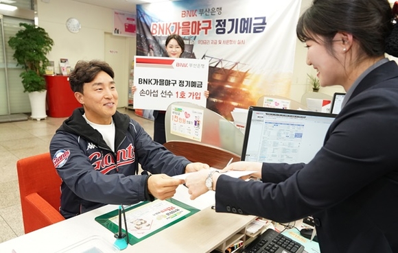 ▲ 지난달 23일 'BNK 가을야구 정기예금' 상품의 새 모델인 롯데자이언츠 손아섭 선수가 부산은행 사직운동장지점을 방문해 1호 고객으로 가입하고 있는 모습. ⓒBNK부산은행