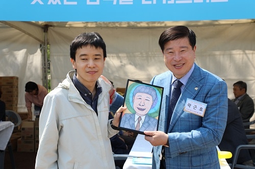 ▲ 곽근호 에이플러스그룹 회장(우측)이 자신의 캐리커처 작품을 그린 참가자와 함께 기념 촬영을 하고 있다.ⓒ에이플러스그룹.