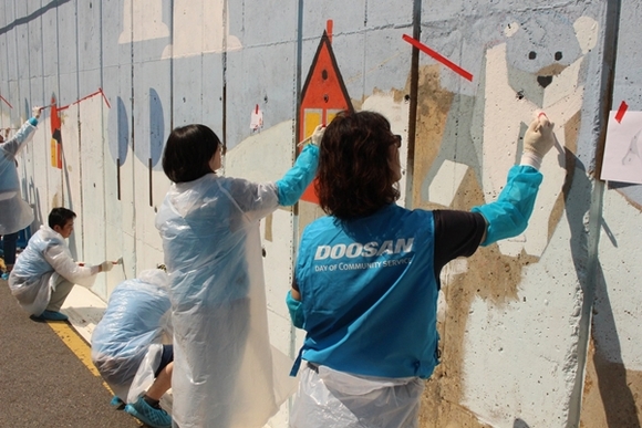 ▲ 오리콤 임직원들이 25일 제6회 '두산인 봉사의 날'을 맞아 벽화그리기 봉사를 시행했다. ⓒ오리콤