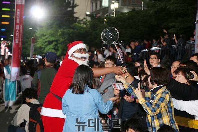 ▲ 퍼레이드 참가 팀 중 산타 복장을 한 참가자가 시민들에게 사탕을 나눠주고 있다.ⓒ뉴데일리