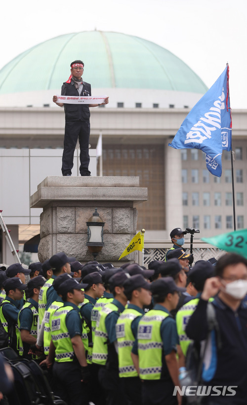 ▲ 지난 21일 서울 여의도 국회 정문 기둥 위에서 민노총 조합원이 국회의 최저임금 산입범위 확대 논의 중단을 요구하고 있다. ⓒ뉴시스