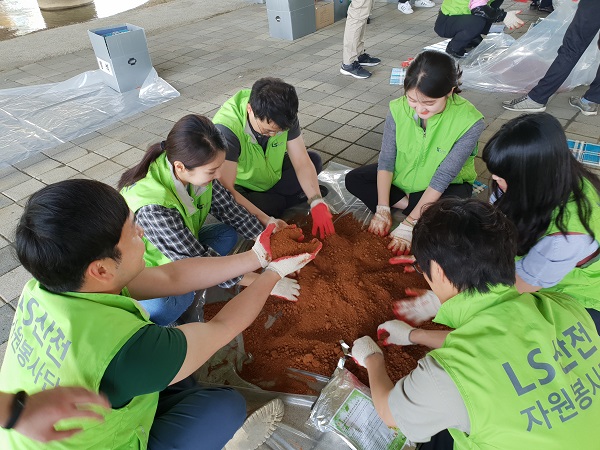▲ LS산전과 협력업체 직원들이 24일 청주 무심천에서 흙공을 만들고 있다.ⓒLS산전 청주사업장