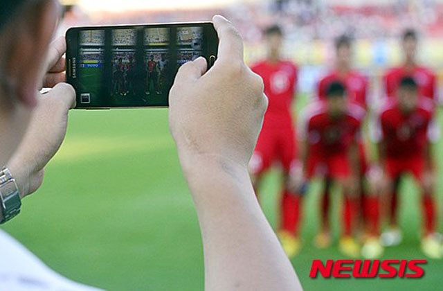 ▲ 2015년 8월 중국에서 열린 동아시안컵 남자대회에서 삼성 갤럭시 폰으로 사진을 찍는 북한 측 관계자. 최근 북한에서는 한국산 휴대전화나 앱을 사용하다 적발되며 가중처벌을 받는다고 한다. ⓒ뉴시스. 무단전재 및 재배포 금지.