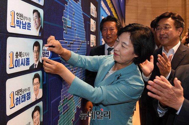 ▲ 6.13 지방선거와 재보궐 선거에서 압승을 거둔 더불어민주당의 추미애 대표가 당선자 이름에 꽃을 달고 있다. ⓒ뉴데일리 DB.