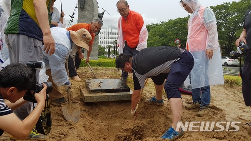 ▲ 28일 오후 경남도청 정문 화단에서 적폐청산과민주사회건설경남운동본부 관계자들이 '홍준표 채무제로 기념표지석'을 파묻는 모습.ⓒ뉴시스