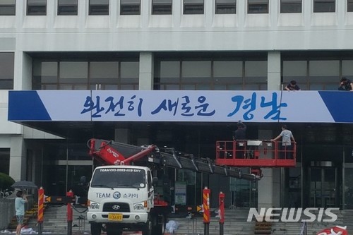▲ 30일 오전 경남도청 본관 건물 가운데 출입구 위에 있던 홍준표 전 도지사의 '당당한 경남시대'가 사라지고, 신임 김경수 도지사의 슬로건인 '완전히 새로운 경남'이 부착되는 모습.ⓒ뉴시스