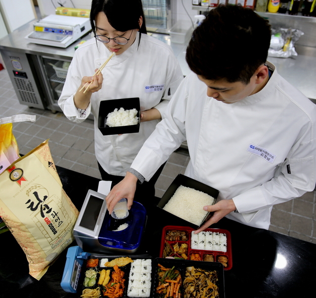 ▲ GS리테일 식품연구소 연구원들이 쌀 품질을 판별하는 기기와 탑라이스로 지은 밥으로 테스트를 진행하고 있다. ⓒGS리테일