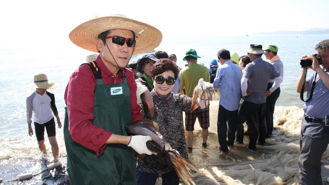▲ 포항 월포해수욕장의 후릿그물 체험 행사에 참각한 이강덕 시장이 함께 참가한 피서객과 잡은 물고기를 보여주고 있다.ⓒ포항시