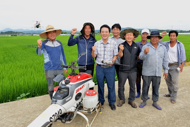 ▲ 달성군은 30일부터 8월 2일까지 전체 벼 재배지역 2,703㏊에 대해 무인헬기방제를 실시한다. 사진은 김문오 군수 등이 벼 재배지역에서 함께 기념사진을 찍은 장면.ⓒ달성군