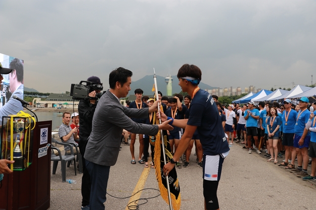 ▲ 미사리 조정경기장에서 열린 제13회 조정대회에서 3연패한 DGIST조정부 김범도 주장(오른쪽)에게 UNIST 곽상규 입학학생처장(왼쪽)이 우승기를 전달하고 있다.ⓒDGIST