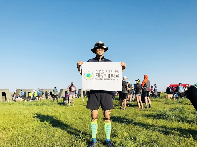 ▲ ‘고비사막마라톤대회’에서 대구대학교 현수막을 들고 기념사진을 찍고 있는 김태환 학생.ⓒ대구대