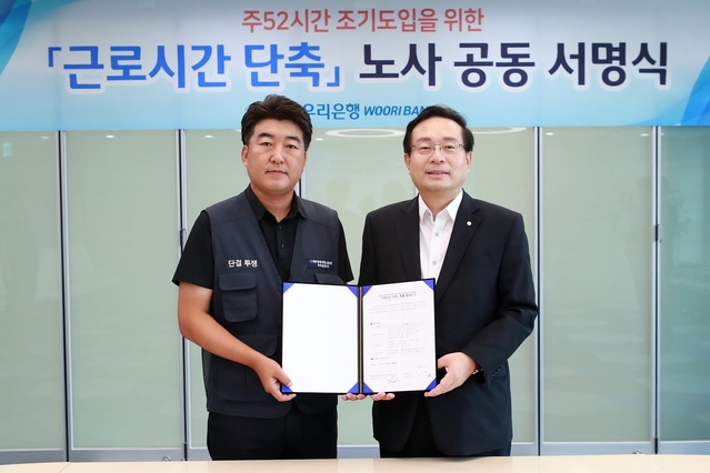 ▲ 우리은행 노사는 일과 가정의 양립을 위해 시중은행 최초로 주52시간 근무제를 10월에 조기 도입하기로 합의했다. 손태승 은행장(사진 오른쪽)과 박필준 노조위원장이 ‘주52시간 조기도입을 위한 노사 공동 서명식’을 실시한 후 기념 촬영을 하고 있다.ⓒ우리은행