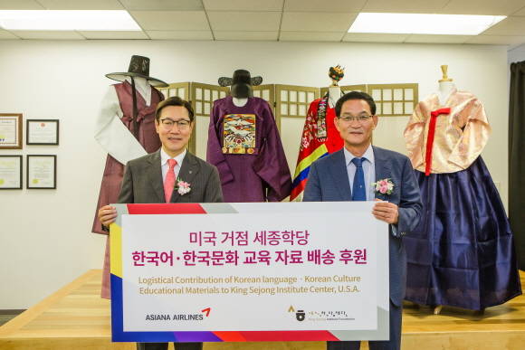 ▲ 김영헌 아시아나항공 미주지역본부장(왼쪽)과 권오기 세종학당재단 이사장 직무대행이 한국어 교육자료를 전달하며 기념촬영을 하고 있다.ⓒ아시아나항공
