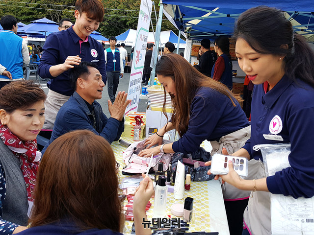 ▲ 랄라블라 직원들이 지난 12일,13일에 경남종합사회복지관에서 진행된 인애사랑 나눔대축제의 뷰티체험 부스에서 네일아트와 헤어스타일링 재능기부 봉사활동을 펼치고 있다. ⓒGS리테일