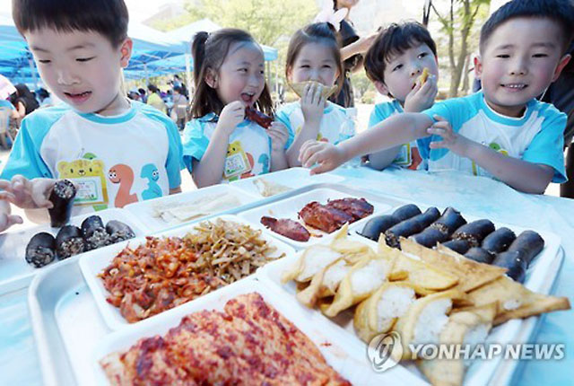 ▲ 2015년 8월 통일부가 주최한 통일박람회에서 북한음식을 먹는 어린이들. 가운데 유부초밥처럼 보이는 것이 인조고기 밥이다. ⓒ연합뉴스. 무단전재 및 재배포 금지.